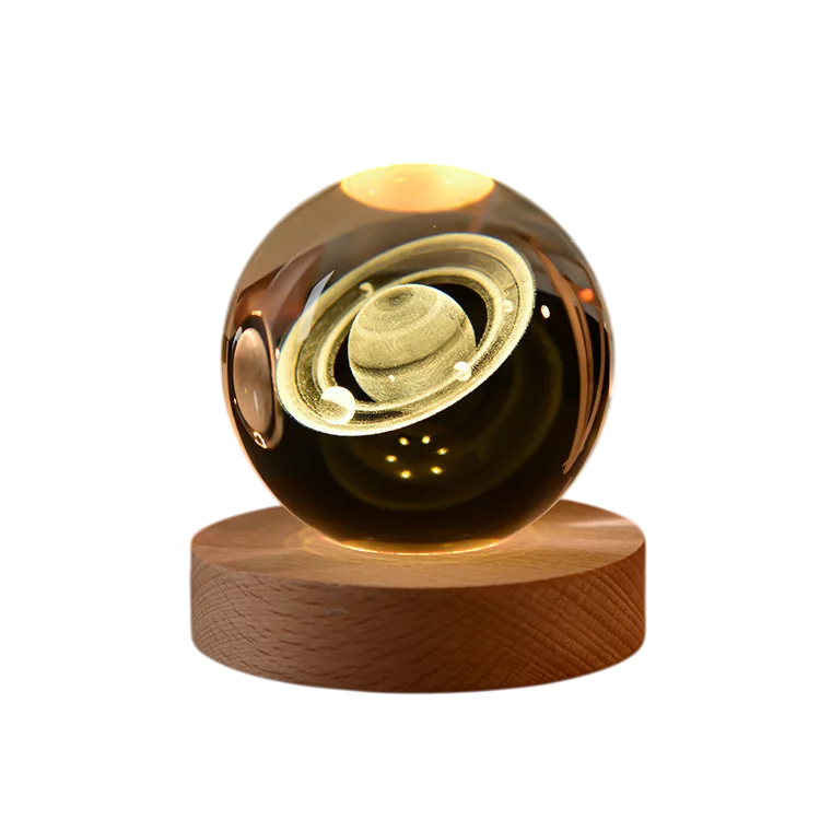 Luminária Decorativa com escultura iluminada do planeta Saturno em tom dourado, dentro de uma bola apoiada em base de madeira - Modelo F